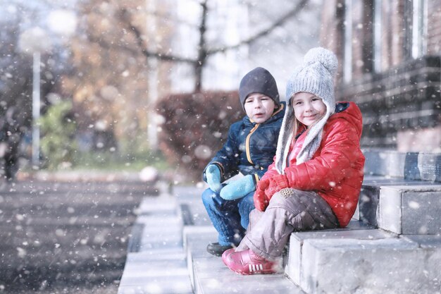 Los niños caminan en el parque con la primera nevada