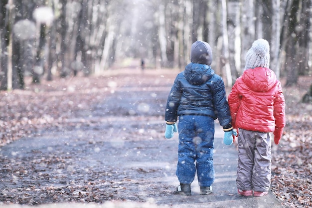 Los niños caminan en el parque primera nevada