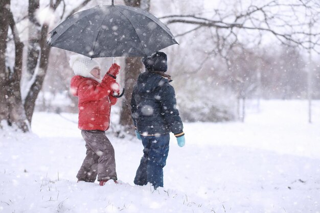 Los niños caminan en el parque primera nevada