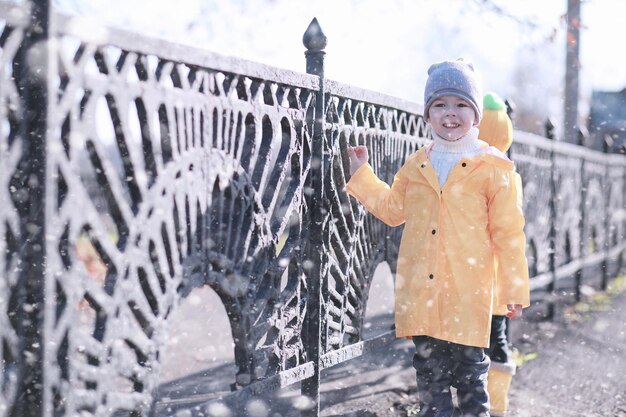 Los niños caminan en el parque con la primera nieve.