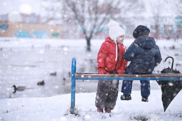 Los niños caminan en el parque con la primera nieve.