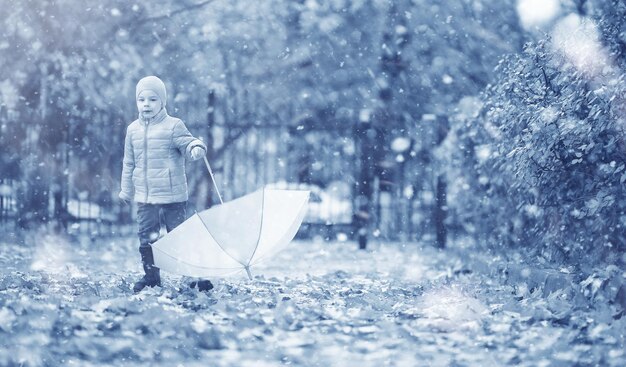 Los niños caminan por el parque con la primera nieve.