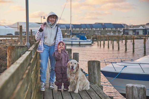 Niños caminando con un perro en el muelle por la noche en Dinamarca