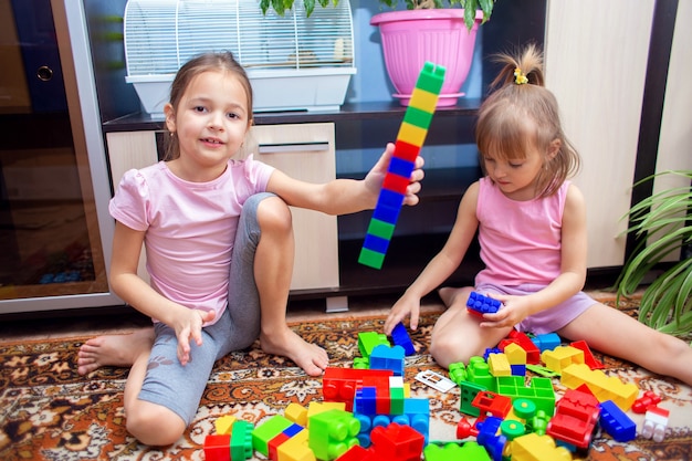 Los niños en casa juegan con un juego de construcción de plástico de color