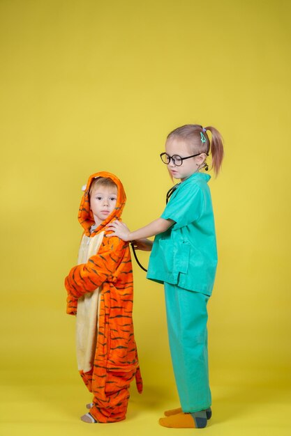 Los niños caucásicos juegan al doctor, un niño disfrazado de tigre vino al pediatra para una cita