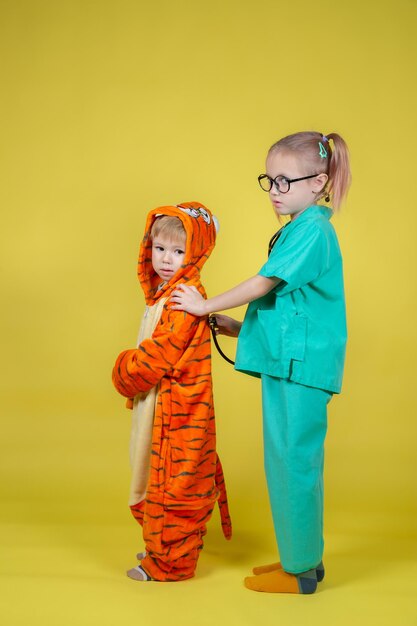 Los niños caucásicos juegan al doctor, un niño disfrazado de tigre vino al pediatra para una cita