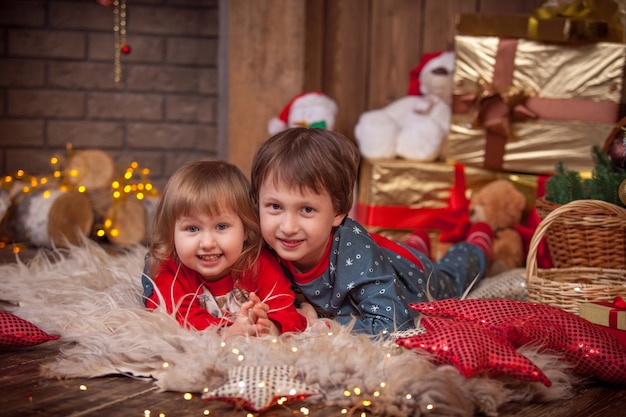 Niños cerca del árbol de Navidad con regalos.