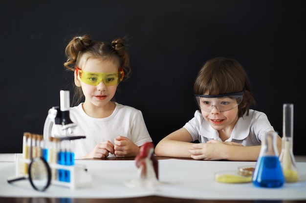Niños científicos Escolares en el laboratorio realizan experimentos Experimentos de niños y niñas con un microscopio