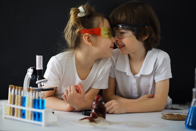 Niños científicos Escolares en el laboratorio realizan experimentos Experimentos de niños y niñas con un microscopio