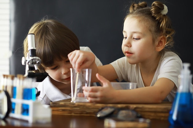 Niños científicos Escolares en el laboratorio realizan experimentos Experimentos de niños y niñas con un microscopio