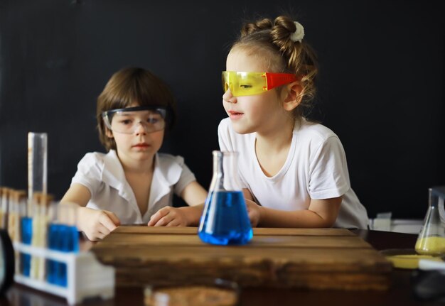 Niños científicos Escolares en el laboratorio realizan experimentos Experimentos de niños y niñas con un microscopio