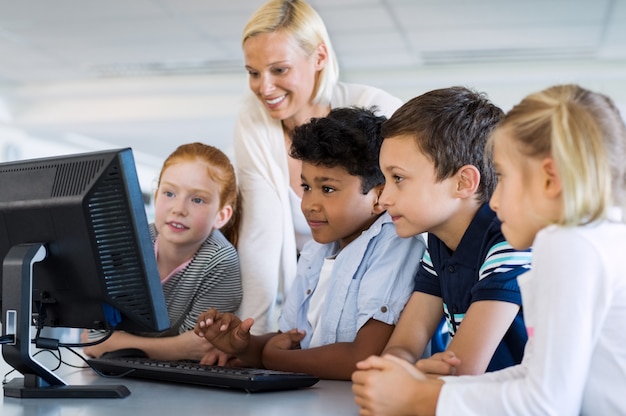 Niños en clase de computación con maestra