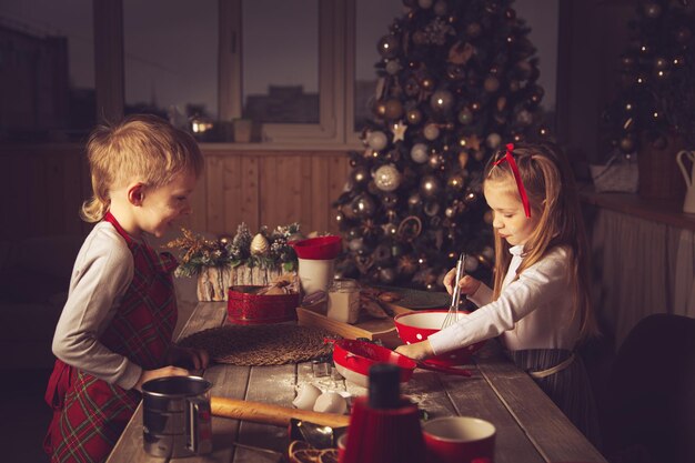 Los niños en la cocina están preparando galletas. Adornos navideños, tradiciones familiares, comida navideña, vísperas de vacaciones.