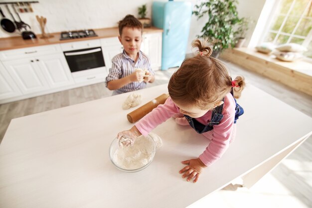 Los niños en la cocina juegan con harina.