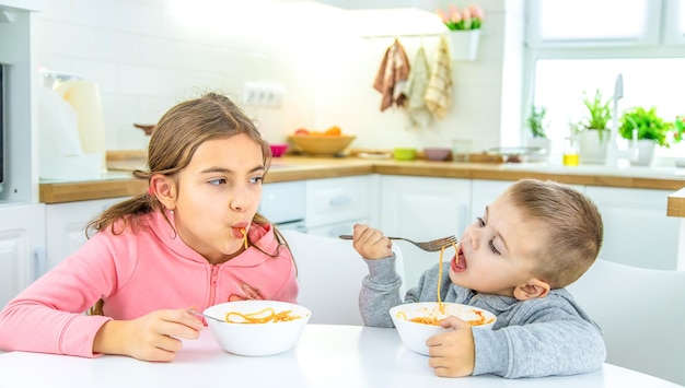 Niños en la cocina en la mesa girando el enfoque selectivo de pasta