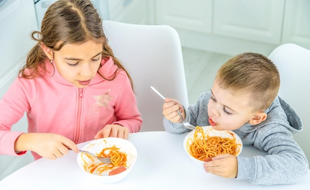 Niños en la cocina en la mesa girando el enfoque selectivo de pasta