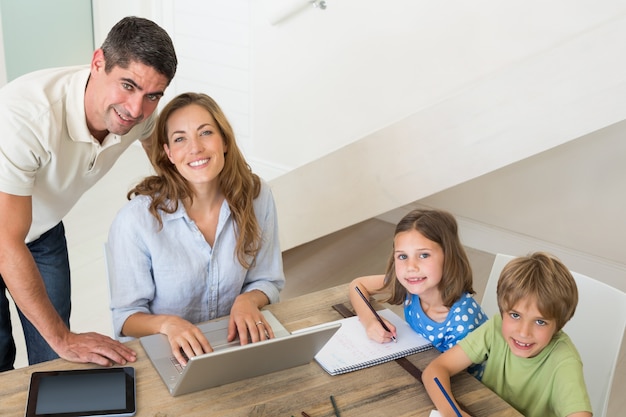 Niños colorear mientras los padres usan la computadora portátil