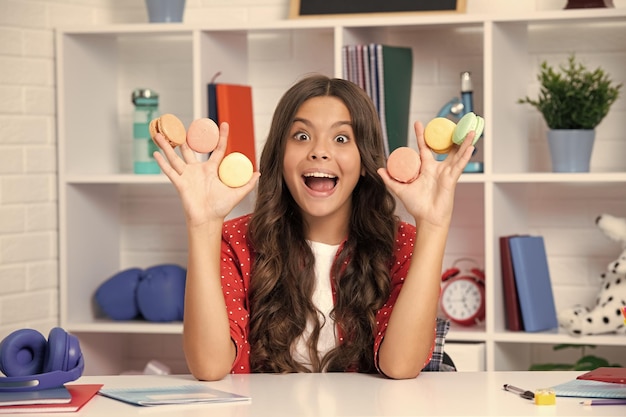 Los niños comen macarrones franceses o galletas de macarrones macarrones Cara emocionada emociones alegres de una adolescente