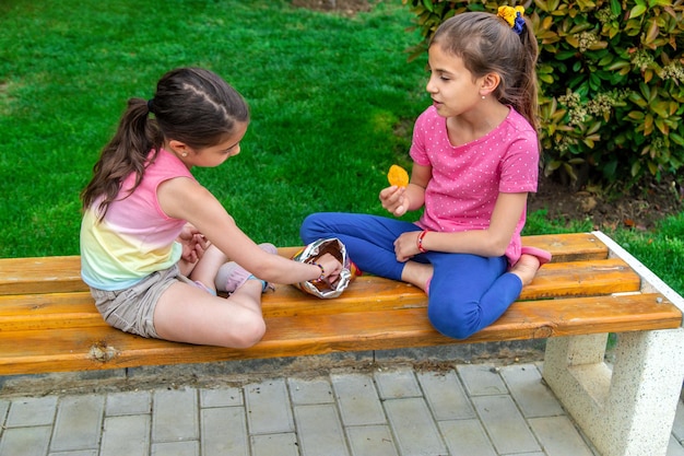 Los niños comen papas fritas en el parque de un amigo Enfoque selectivo