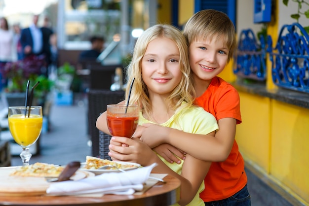 Los niños comen pizza y beben jugo al aire libre.