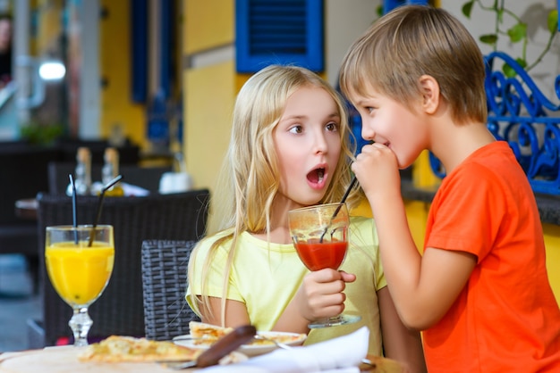 Los niños comen pizza y beben jugo al aire libre.