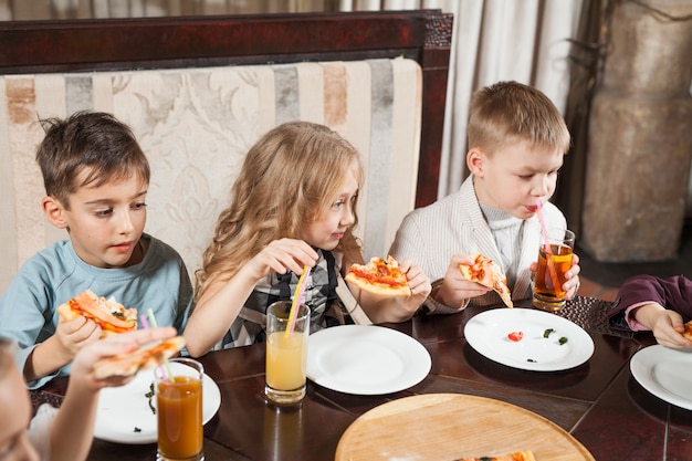 Los niños comen pizza en un restaurante.