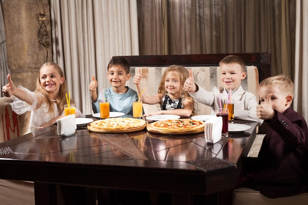 Los niños comen pizza en un restaurante.