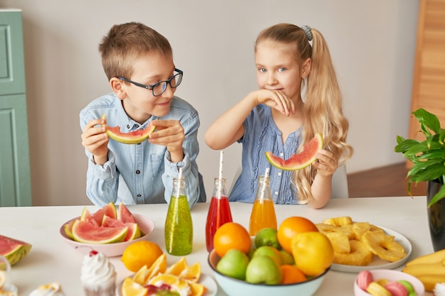 Los niños comen rodajas de sandía en la cocina