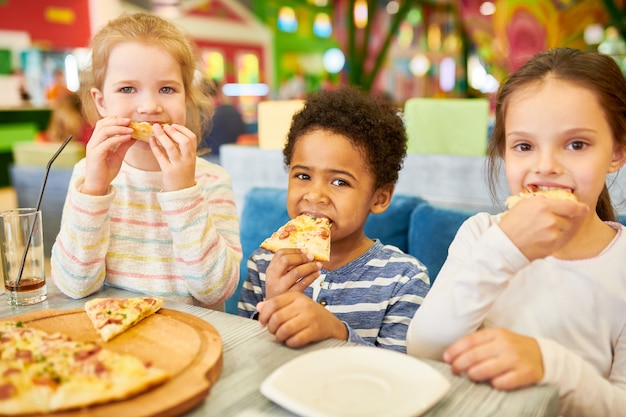 Foto niños comiendo pizza en café