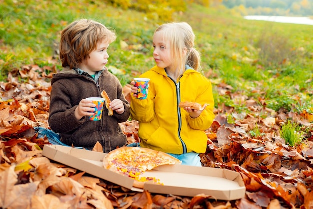 Niños comiendo pizza en la caída de hojas de arce otoñal concepto de estilo de vida infantil de fondo