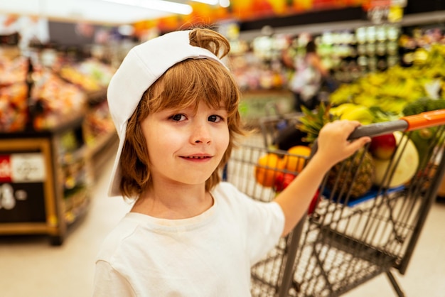 Los niños compran alegres y hermosos niños en el supermercado compran verduras alimentos saludables para los niños