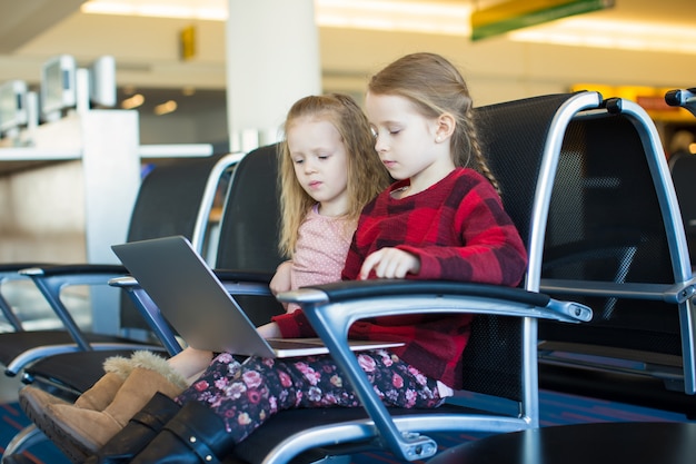 Niños con una computadora portátil en el aeropuerto mientras esperan su vuelo