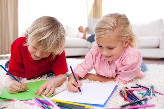 Niños concentrados dibujando tirado en el piso