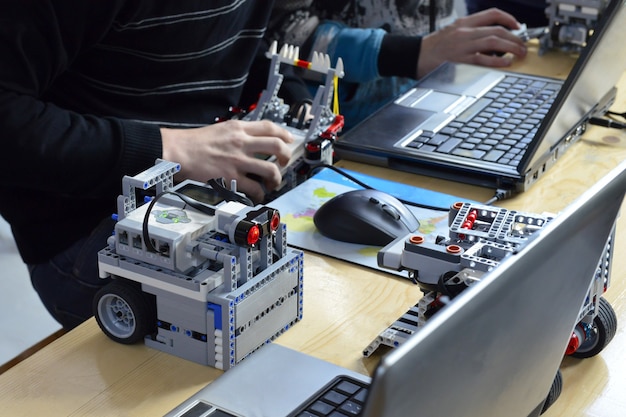 Los niños construyendo robots cerca del edificio del niño desde la educación de la creatividad de programación del constructor