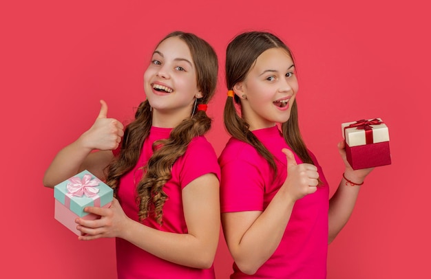 Foto niños contentos con cajas de regalos en fondo rojo