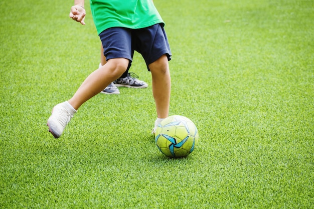 Niños corriendo y pateando balón de fútbol.