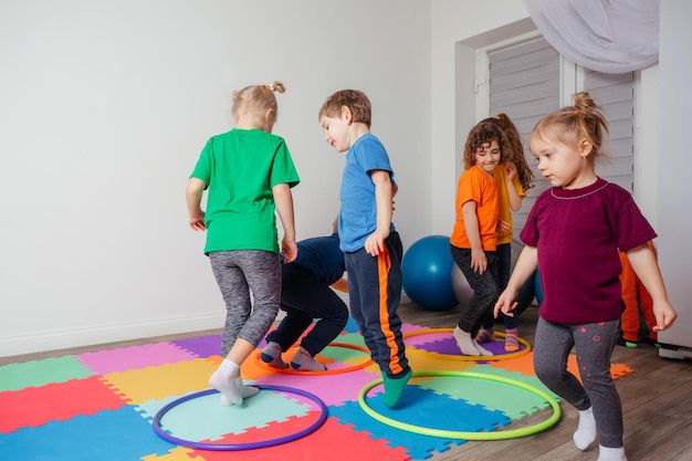 Niños corriendo y saltando alrededor de aros multicolores en un piso