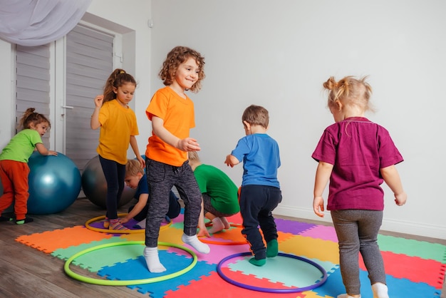 Niños corriendo y saltando alrededor de aros multicolores en un piso