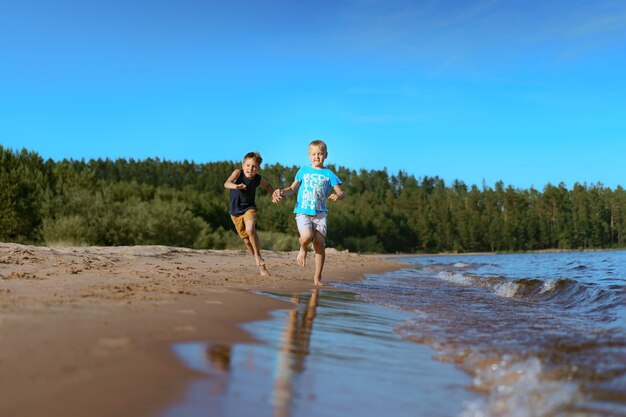 Niños corriendo solo en la playa. puesta de sol y cielo azul. Concepto de infancia feliz. Foto de alta calidad