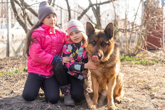 Niños corriendo con su cachorro de pastor alemán en el parque