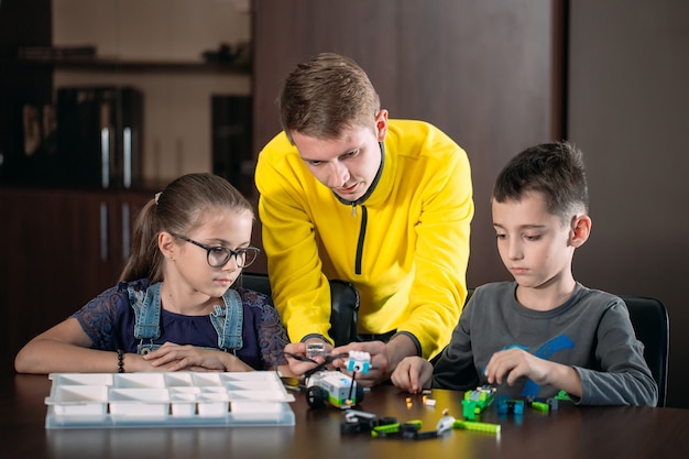 Niños creando robots con el maestro. Desarrollo temprano, bricolaje, innovación, tecnología moderna.