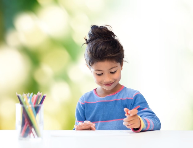 niños, creatividad y concepto de gente feliz - niña feliz dibujando con lápices de colores sobre fondo verde