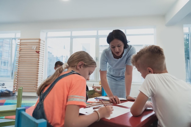 Niños creativos durante una clase de arte en una guardería o en un salón de clases de la escuela primaria dibujando con una maestra