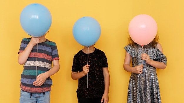 Niños cubriendo caras con globos.