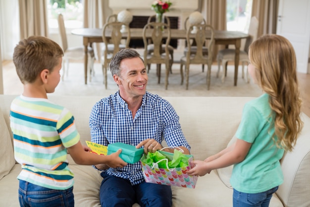 Niños dando un regalo sorpresa a su padre