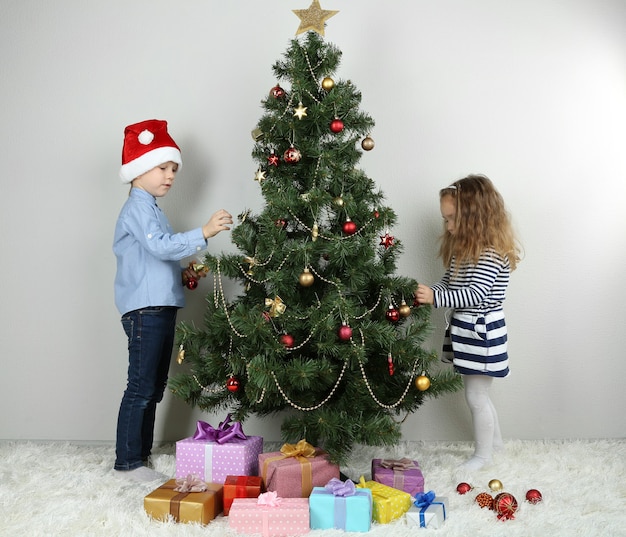 Niños decorando el árbol de Navidad con adornos en la habitación