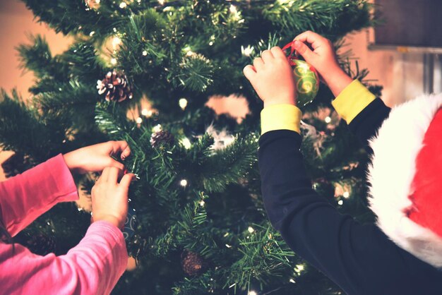 Foto niños decorando el árbol de navidad en casa