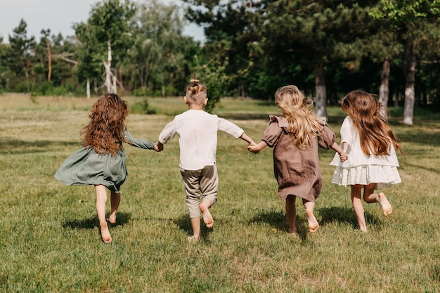 Niños descalzos corriendo en un campo con hierba verde