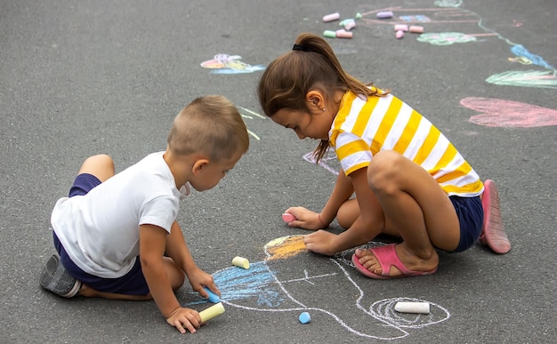 Foto los niños dibujan en el pavimento con tiza muy buen clima enfoque selectivo