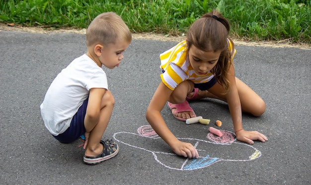 Los niños dibujan en el pavimento con tiza Muy buen clima enfoque selectivo